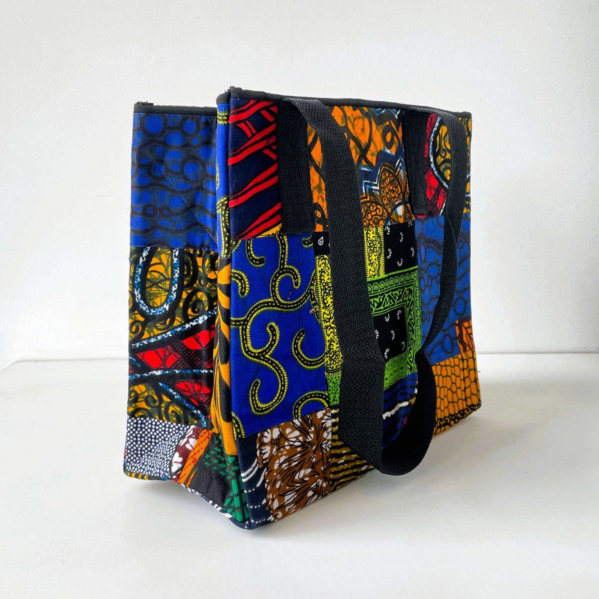 Colorful patterned bag with a black strap on a white background