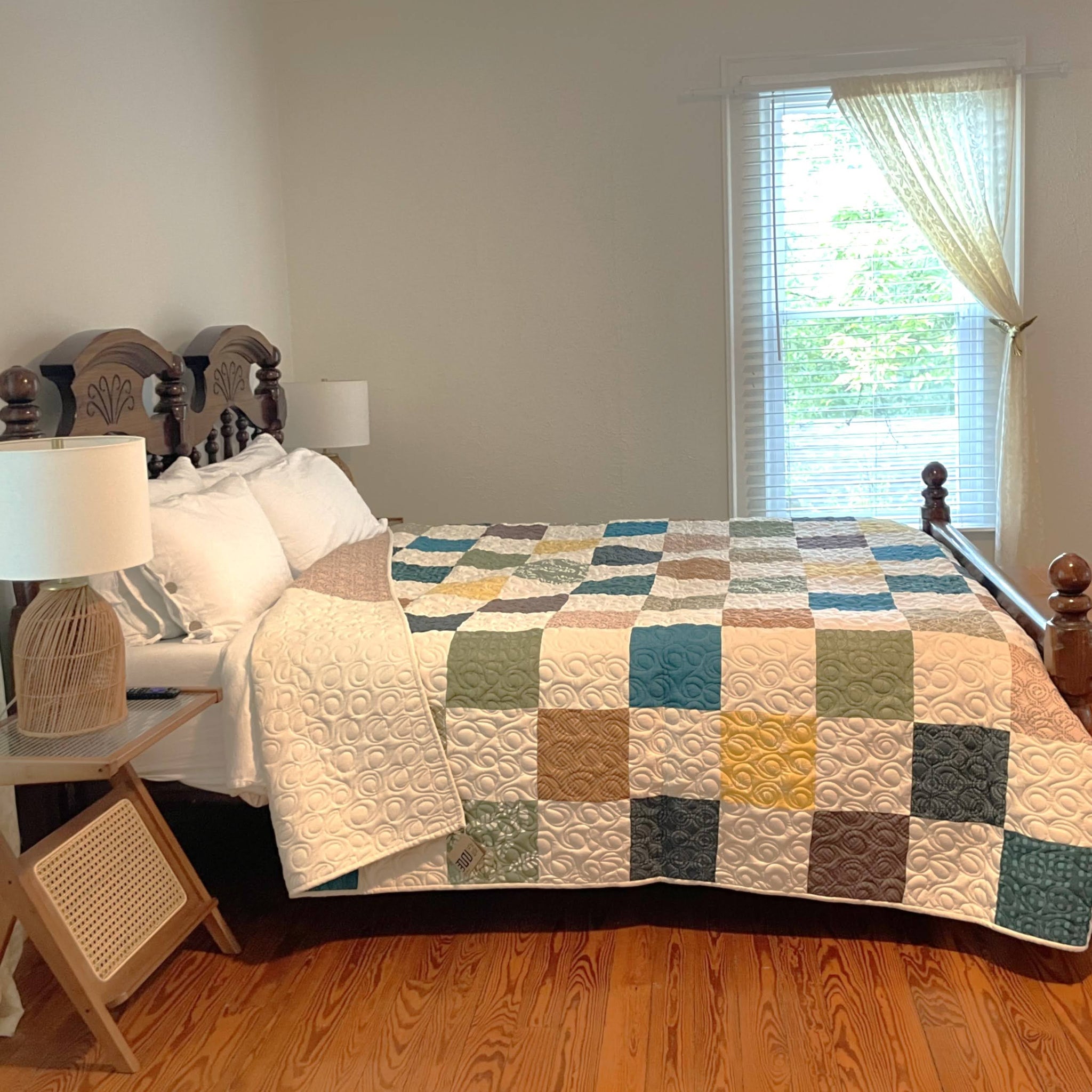 Bedroom with a bed covered by a patchwork quilt, wooden headboard, and lamp on a nightstand.
