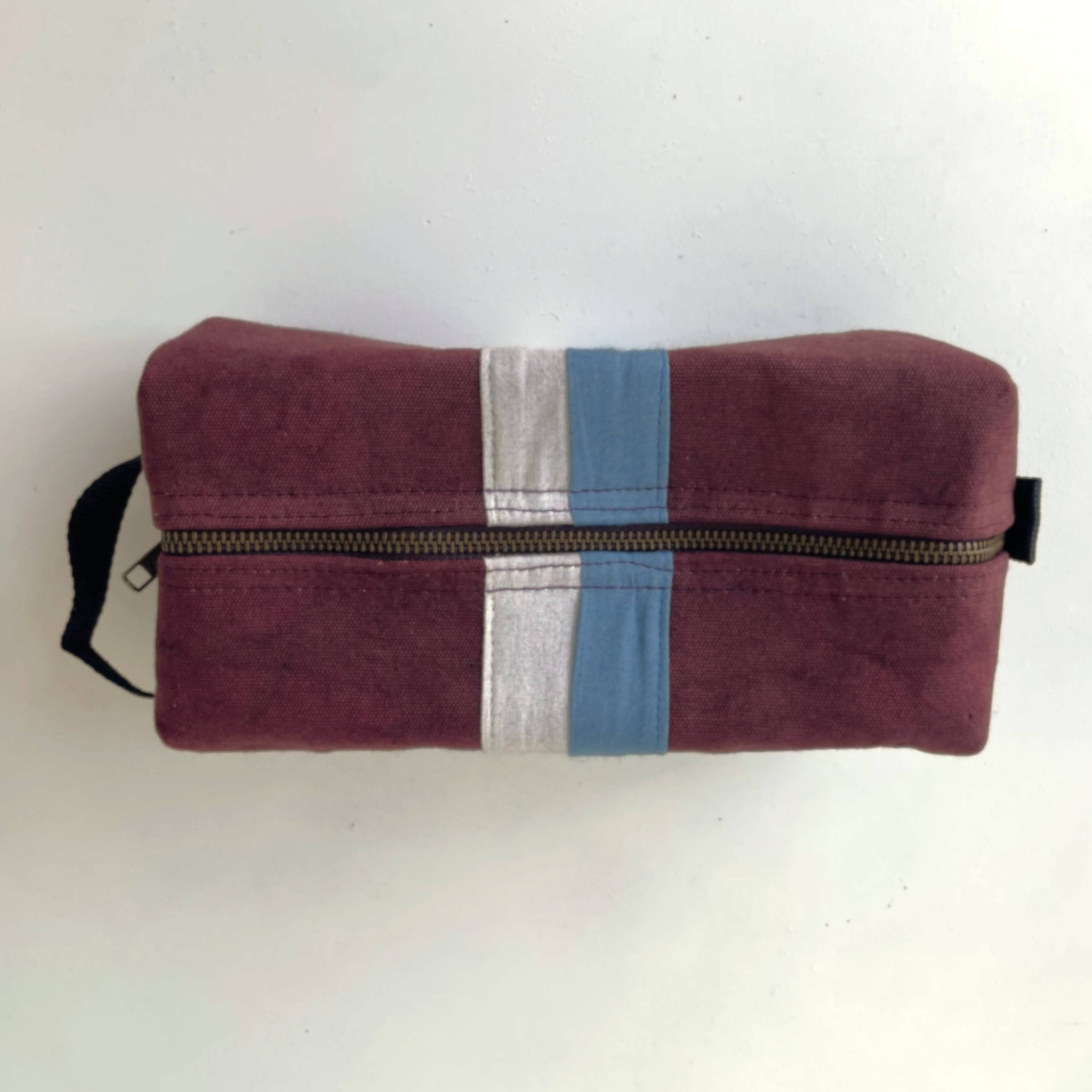 Plum toiletry bag with a blue and gray stripe on a white background