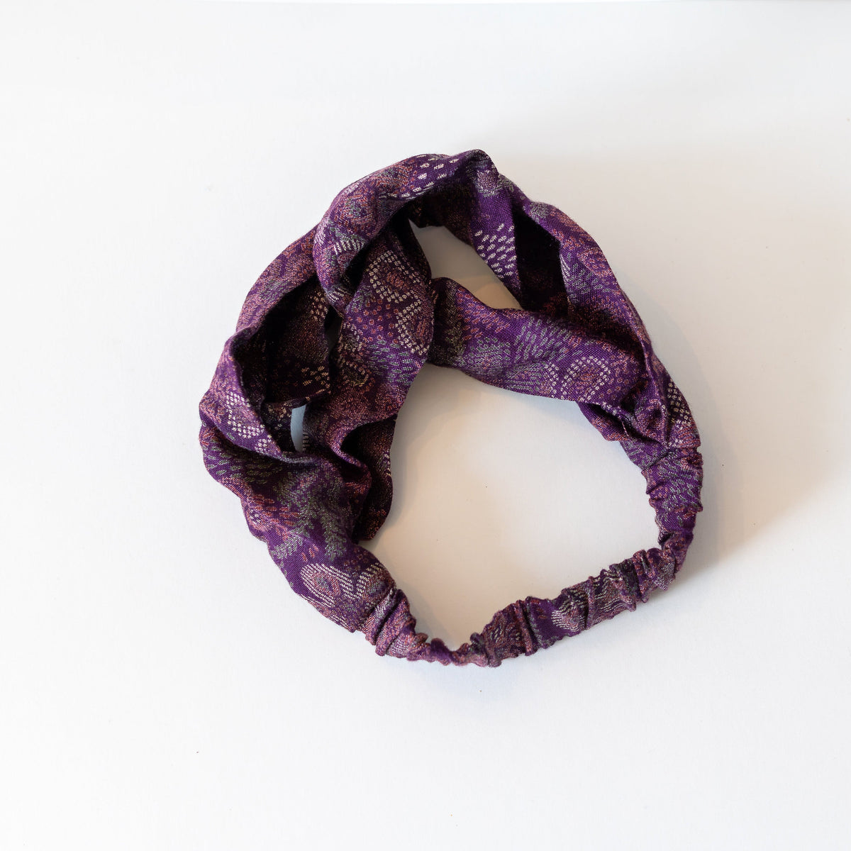 Purple patterned twisted headband on a white background.