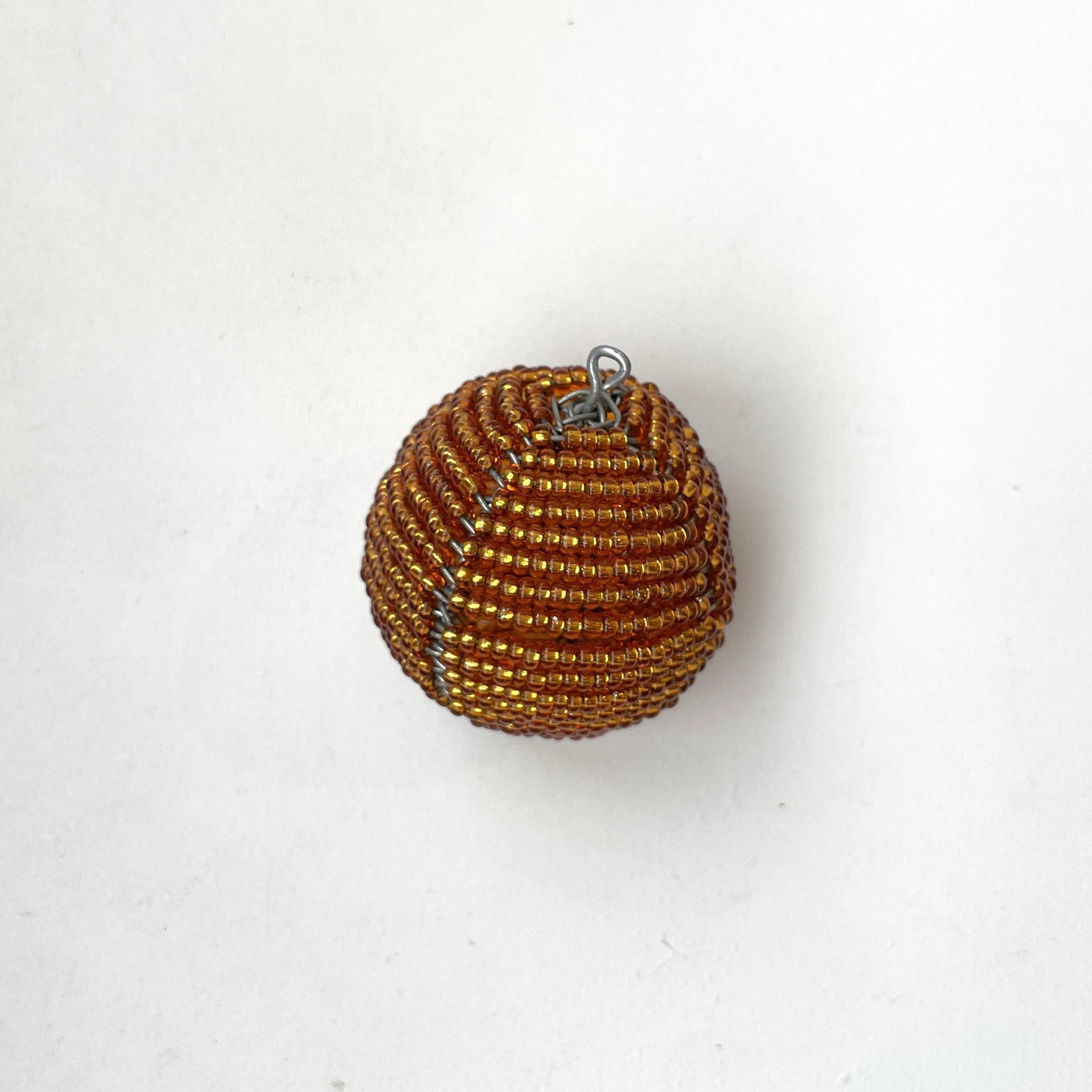 Gold beaded ball with a hanger on a white background