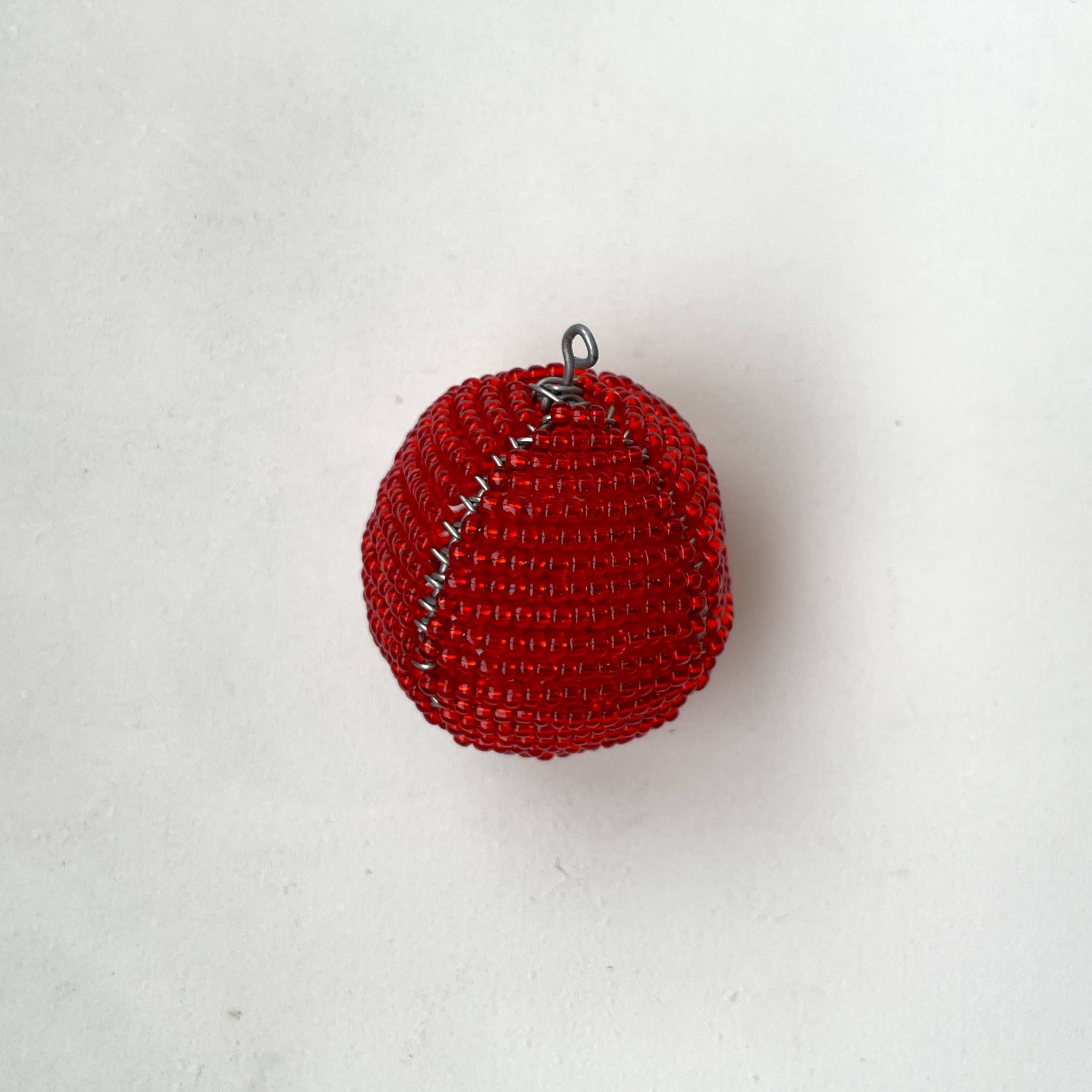 Red beaded ball with a hanger on a light gray background
