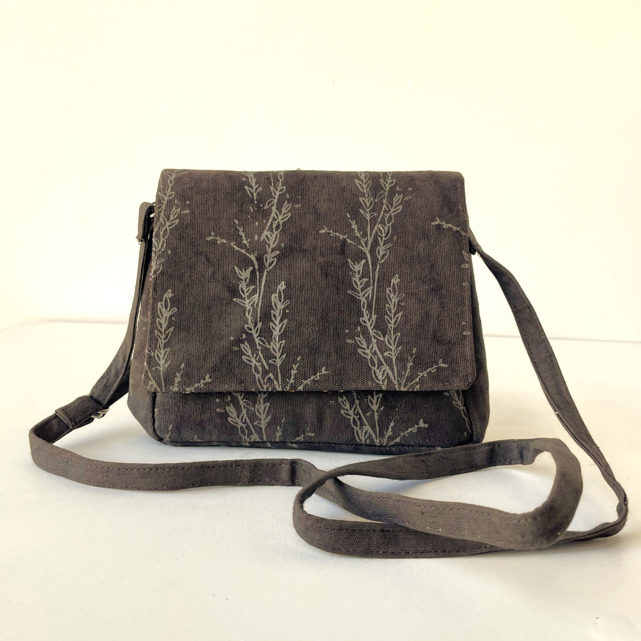 Grey crossbody bag with stem pattern on white background