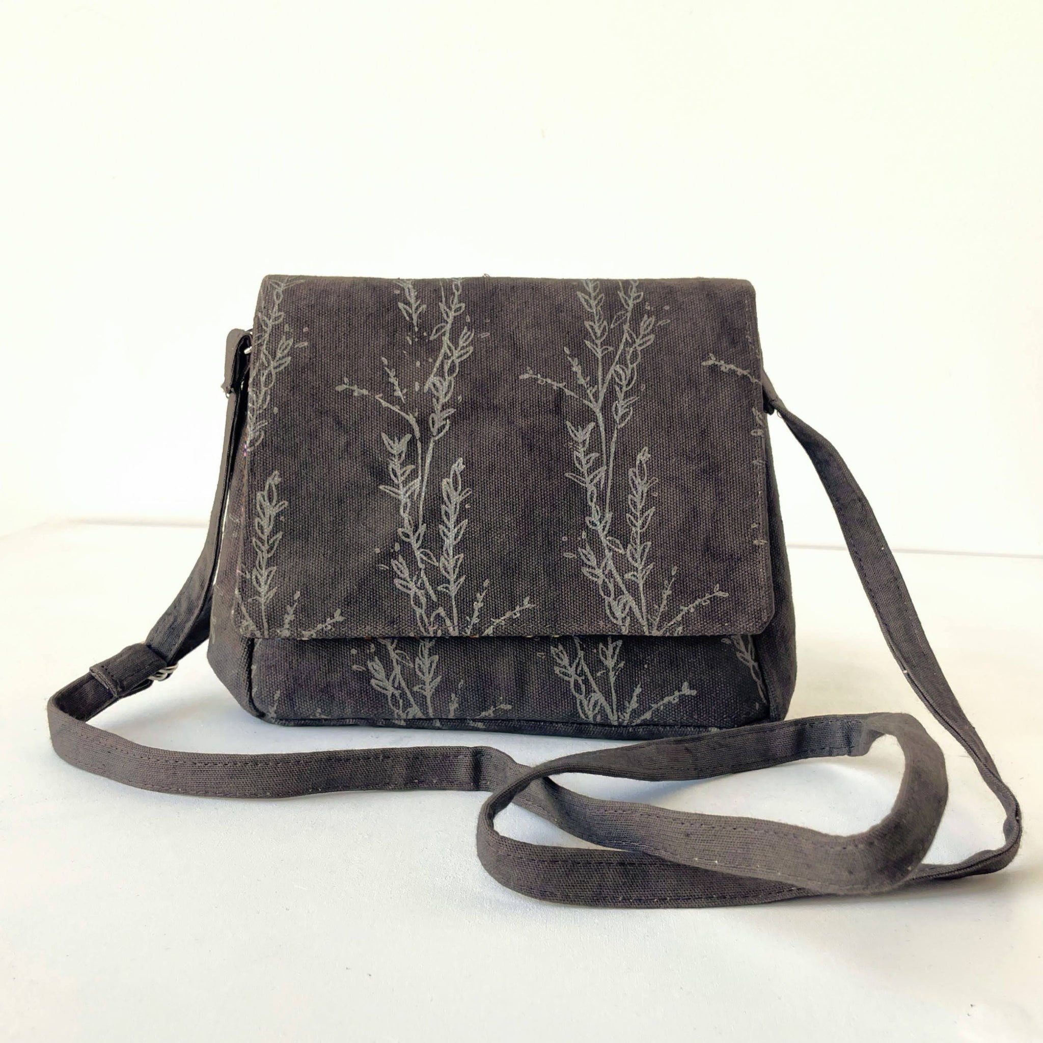 Dark gray crossbody bag with floral pattern on a white background