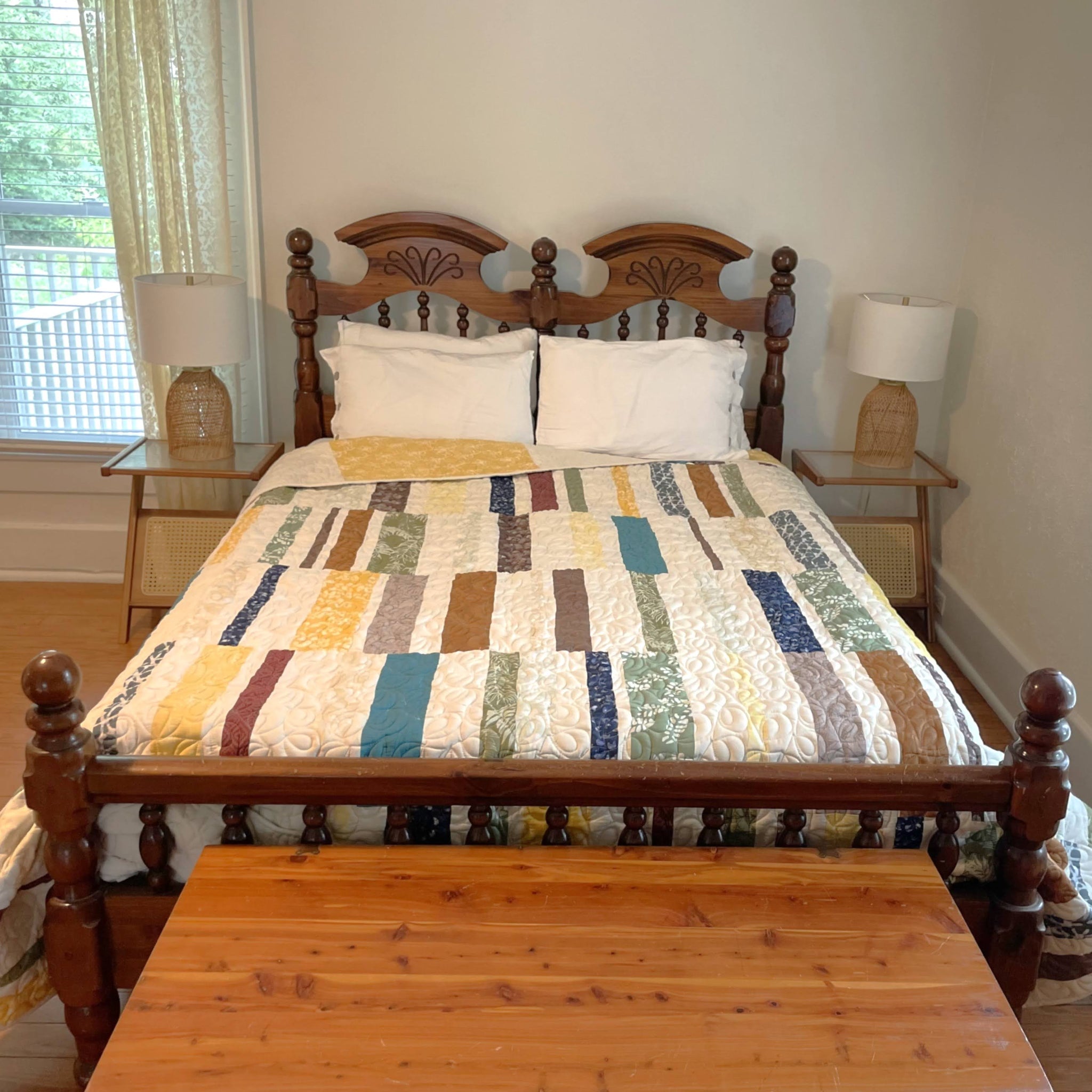 Bedroom with a wooden bed and nightstands featuring a colorful quilt.