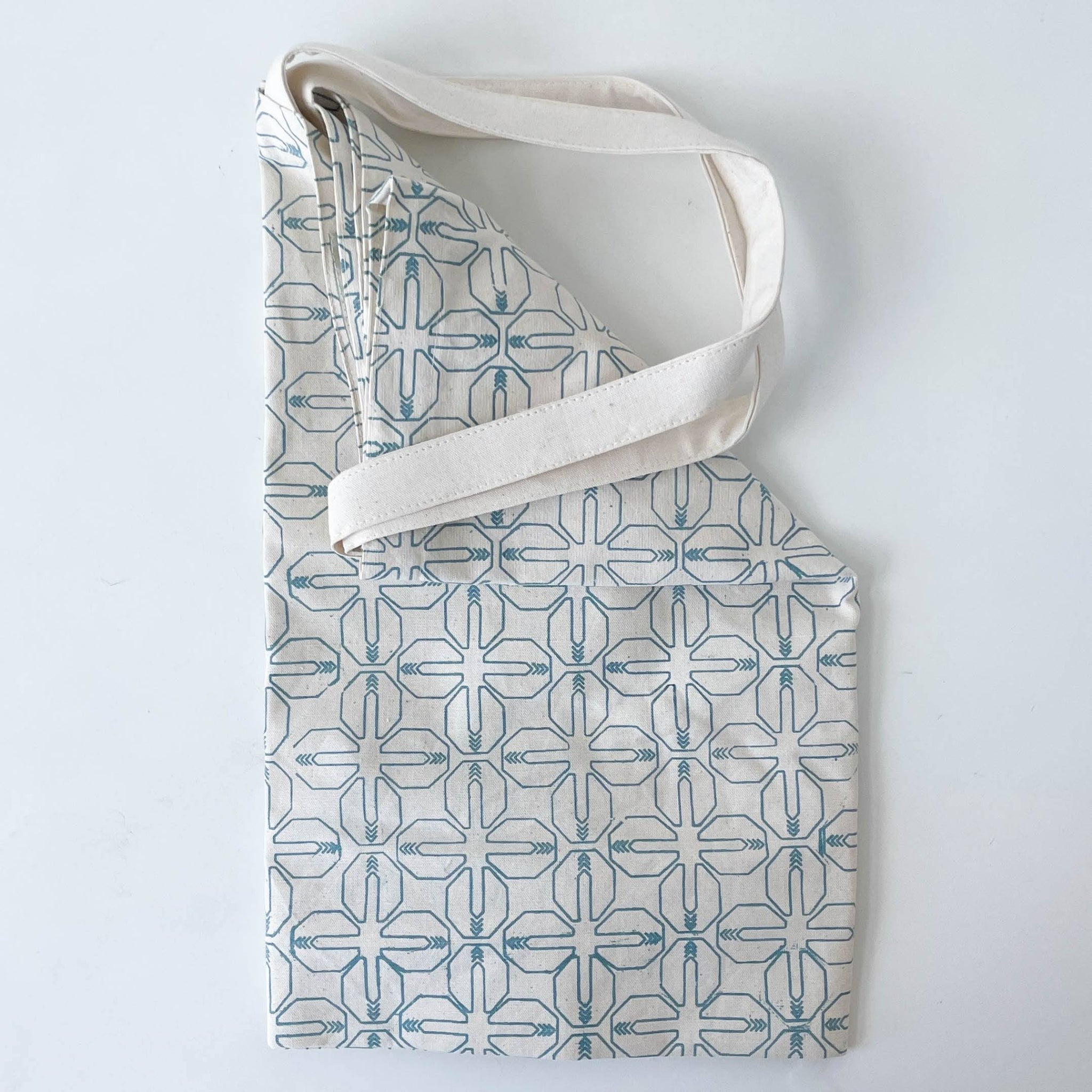 Tote bag with geometric pattern and white strap on a light gray background