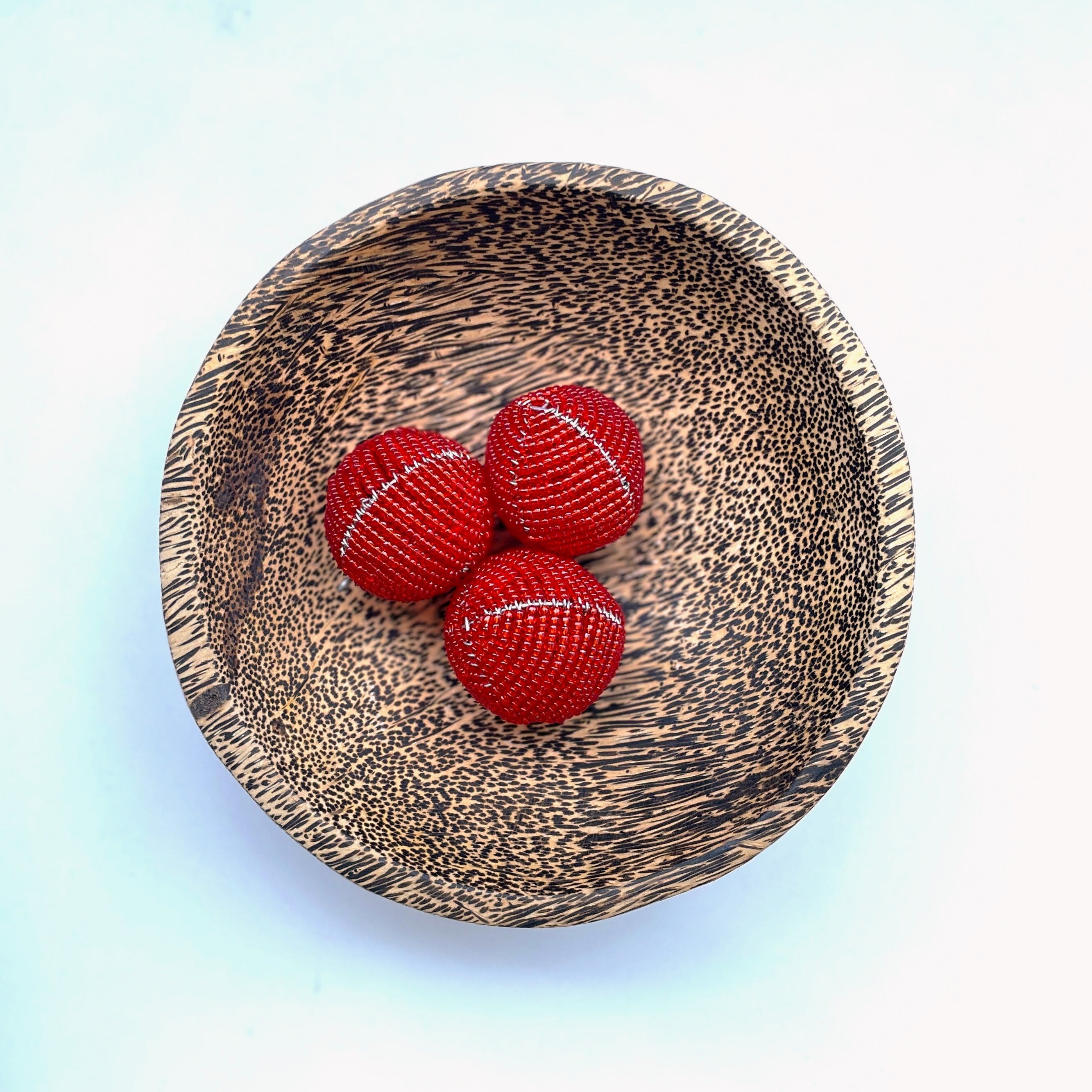 Wooden bowl with red beaded balls on a gradient background