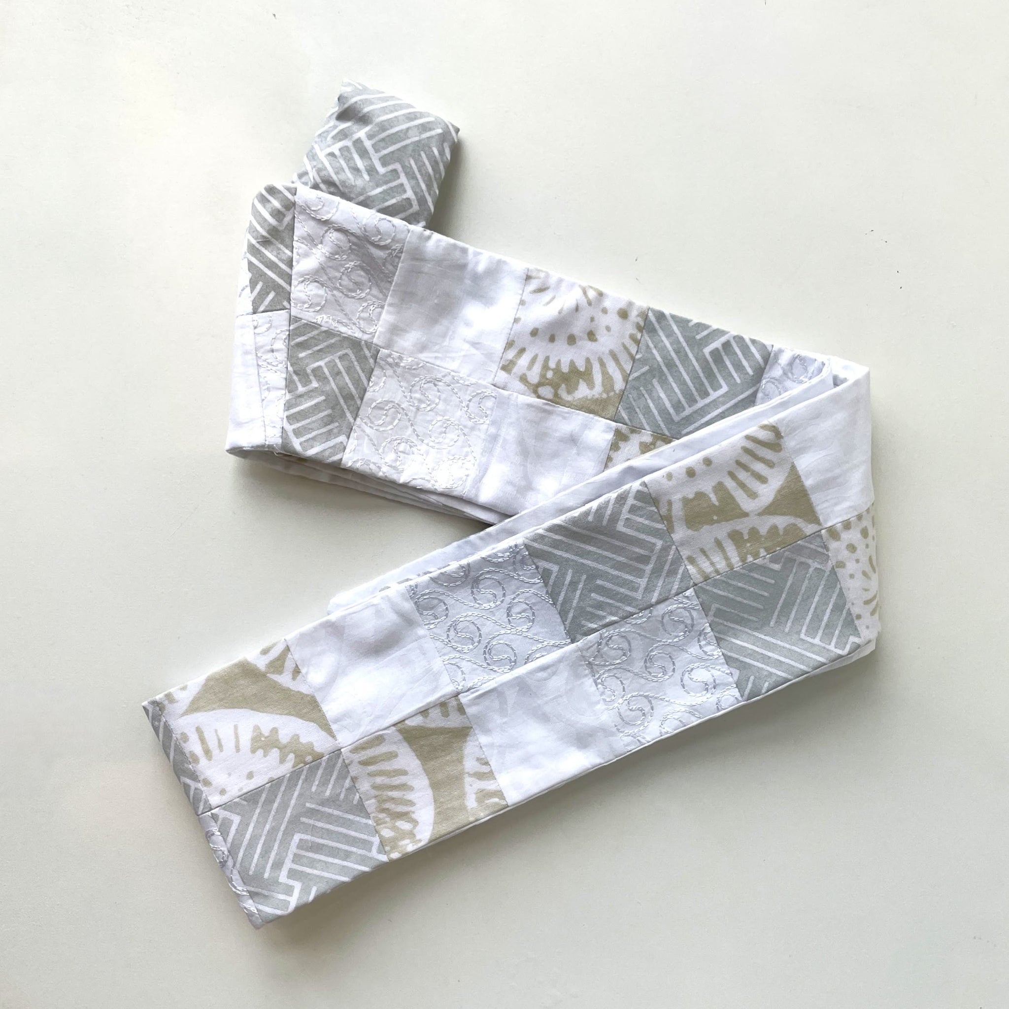 Folded fabric stole with geometric patterns on a light background
