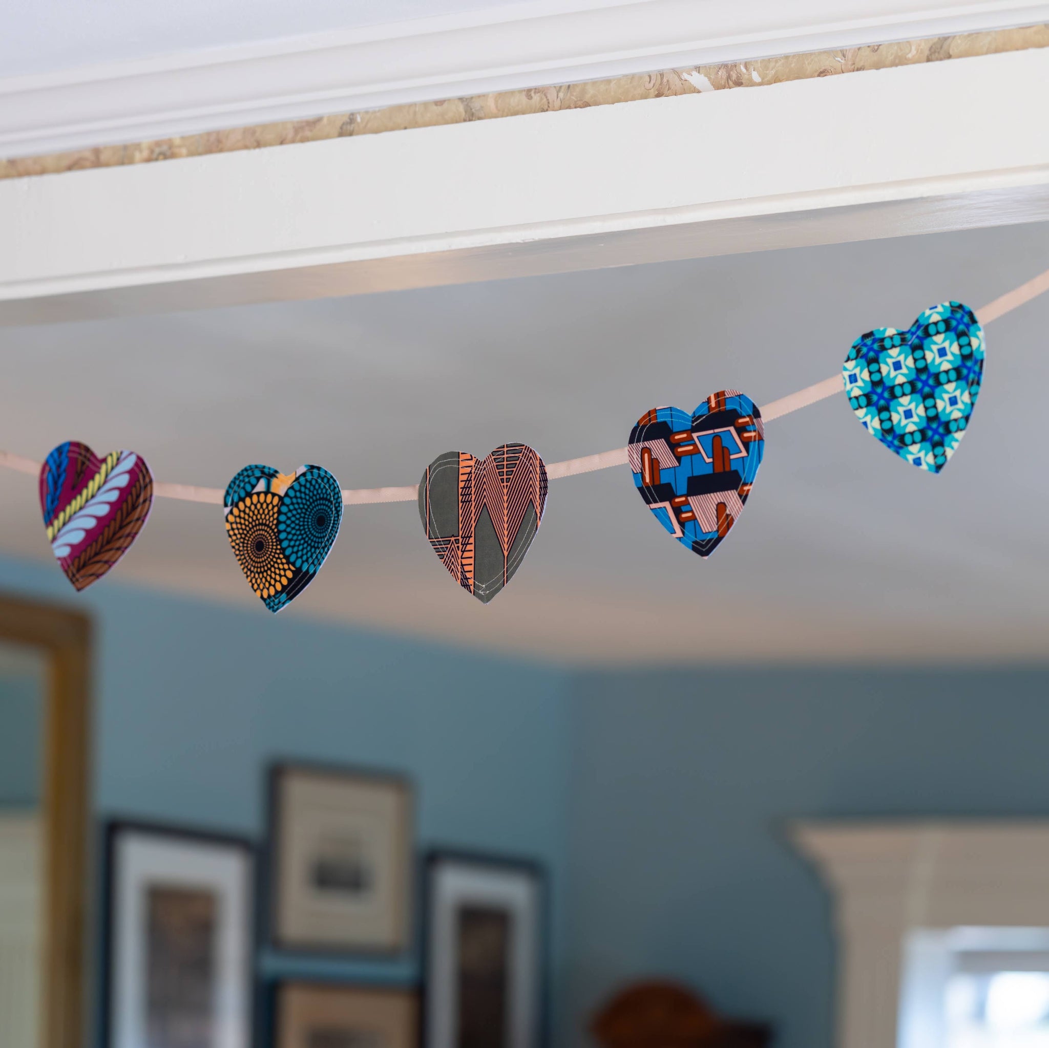 A string of heart-shaped fabric garland pieces in assorted patterns and colors hanging across a doorway in a home interior.