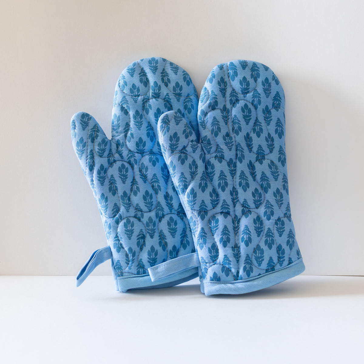 Pair of blue floral oven mitts with a light background