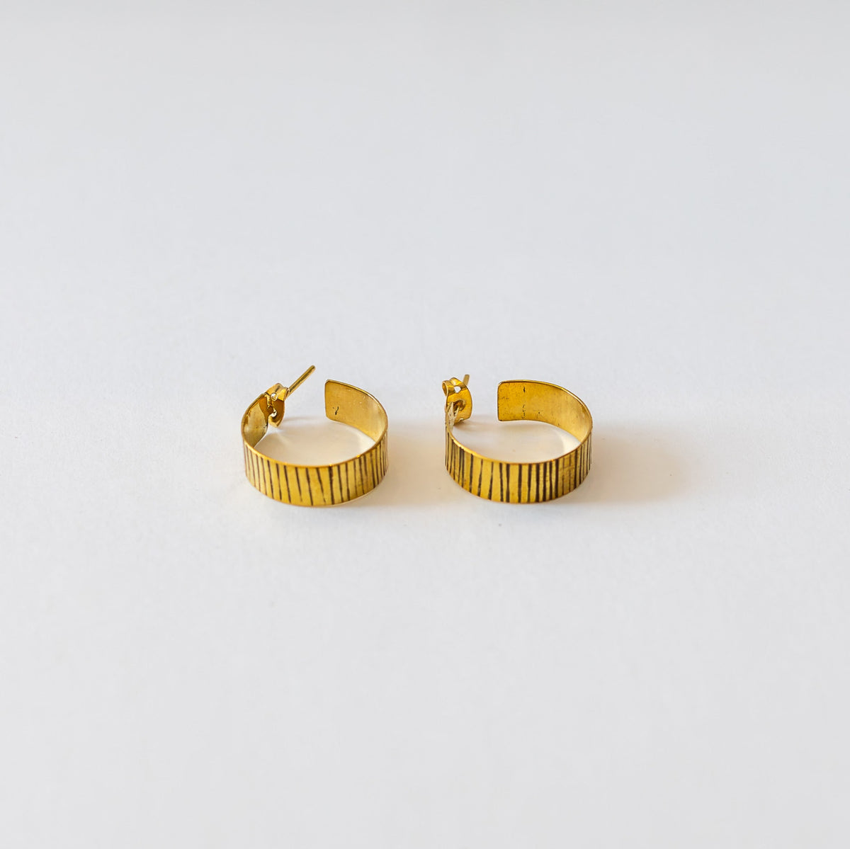 Etched brass hoop earrings on a white surface