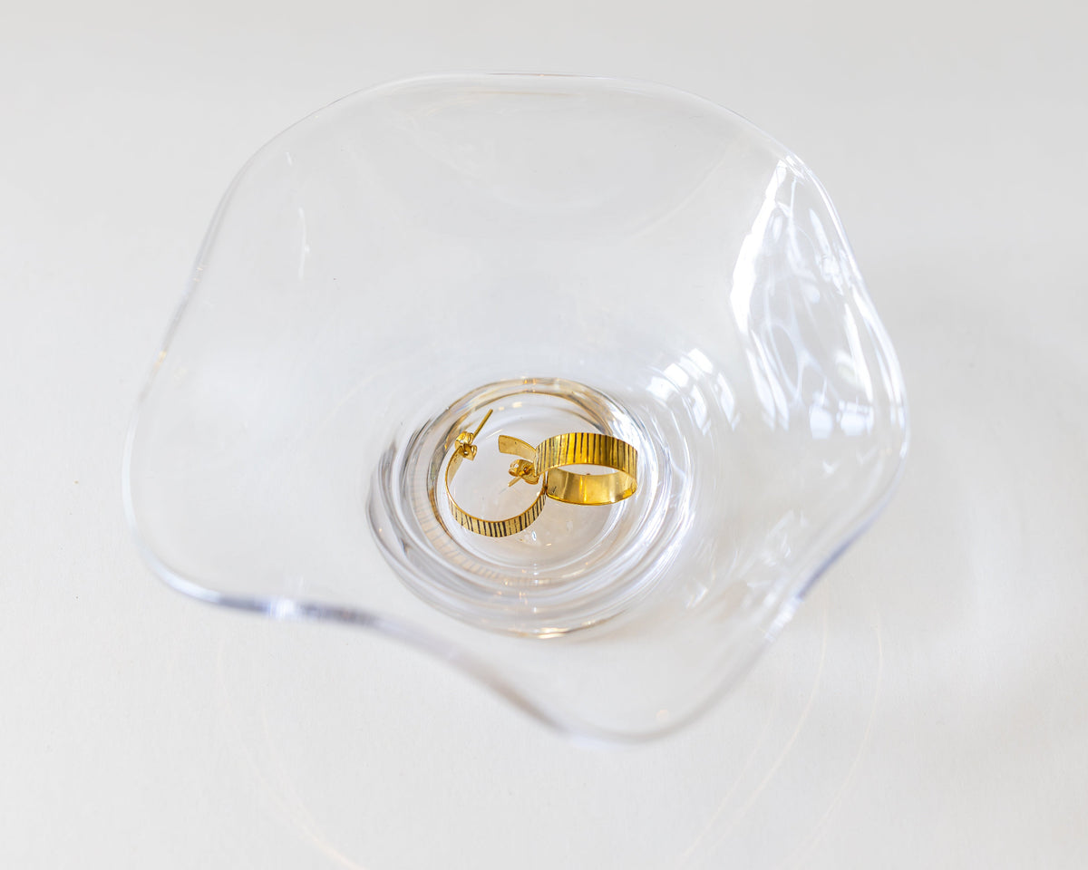 Etched brass hoop earrings in a clear glass dish