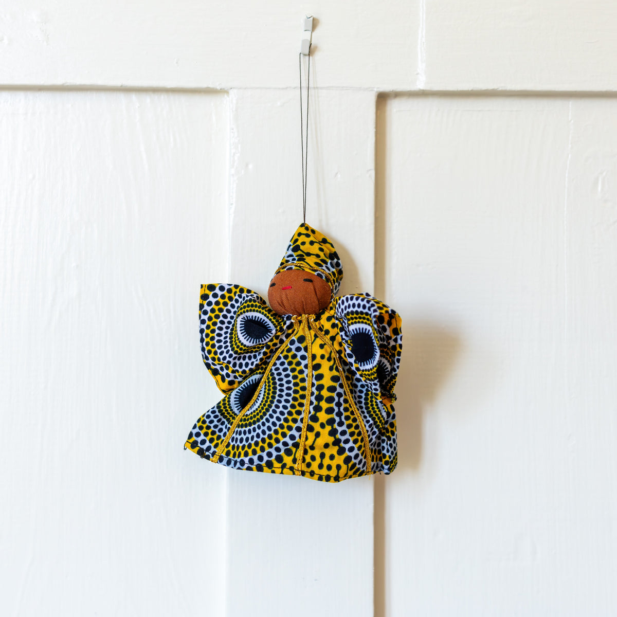 Navy and gold fabric peace angel ornament hanging on a white door