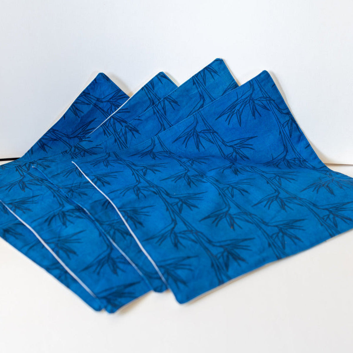 Set of blue placemats with bird of paradise print on a white background
