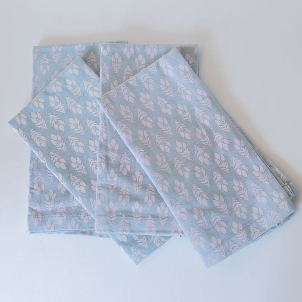 Set of pale blue napkins with white bouquets on a white surface