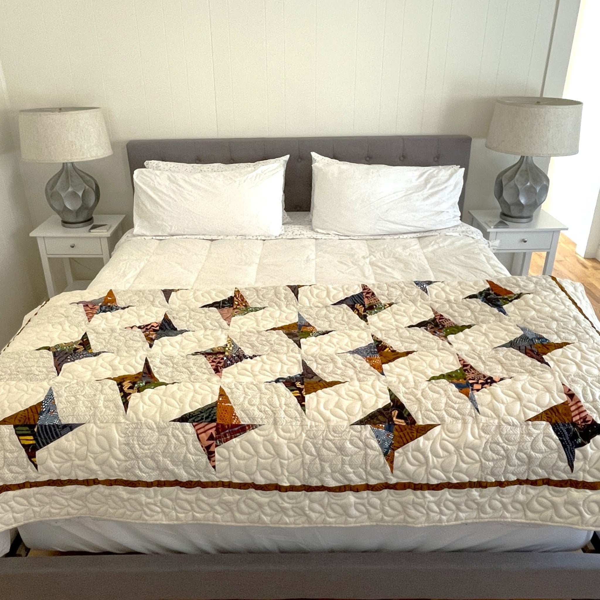 Bed with a patterned quilt and white pillows in a bedroom setting.