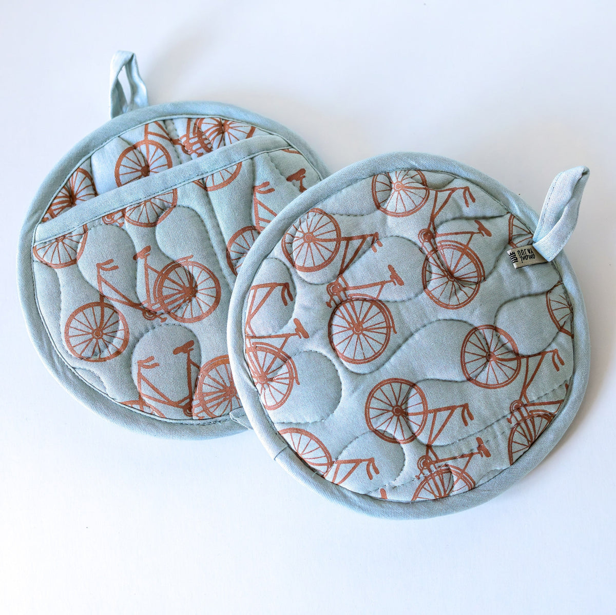 Set of blue pie mitts with bicycle pattern on light background