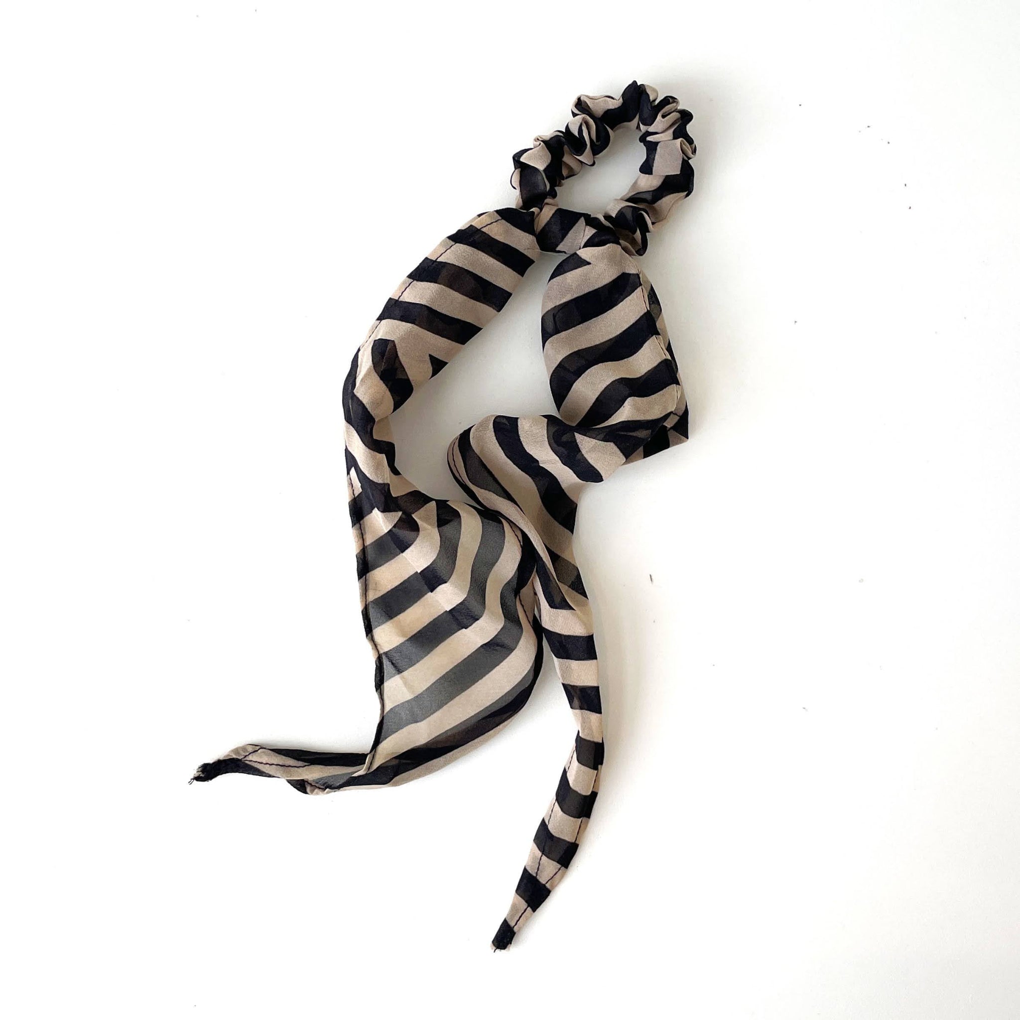 Black and beige striped scarf with a scrunchie on a white background