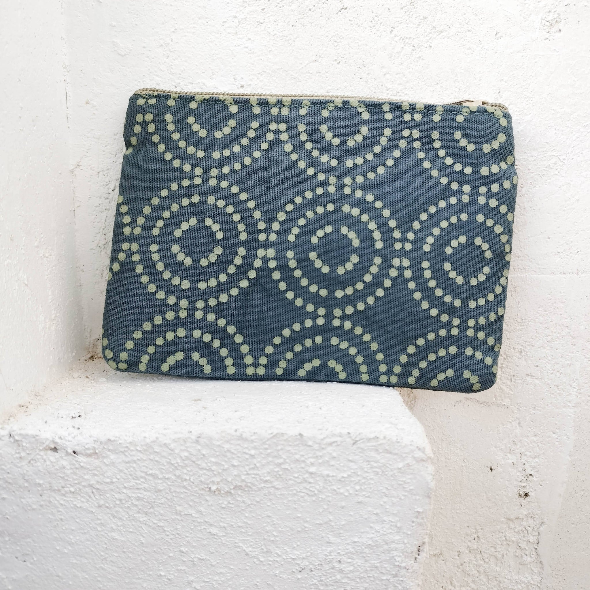 Blue pouch with circular pattern on a white textured surface