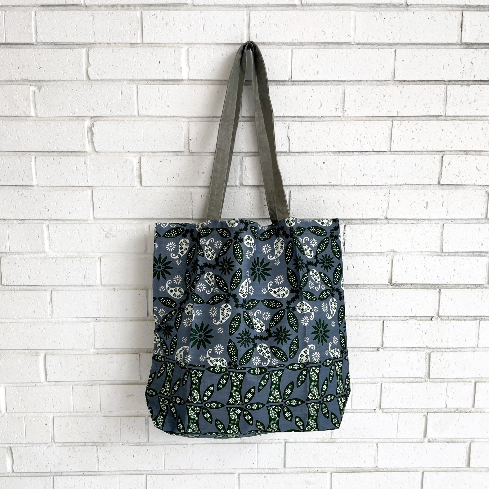 Tote bag with floral pattern hanging against a white brick wall