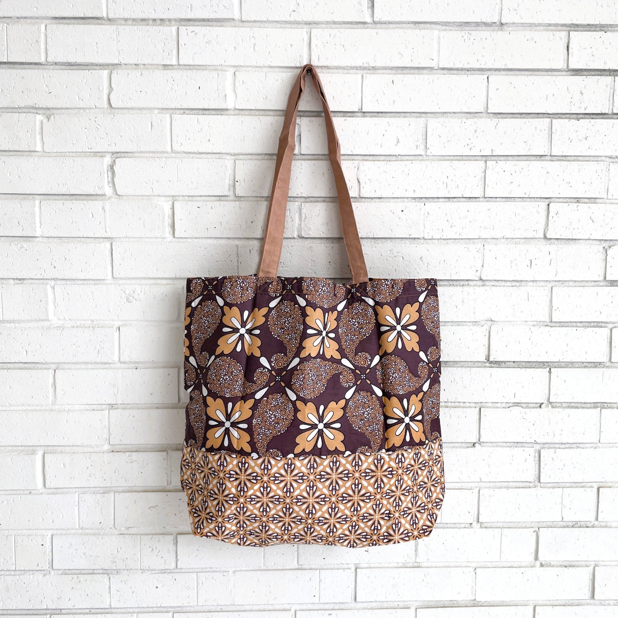 Tote bag with floral pattern hanging against a white brick wall