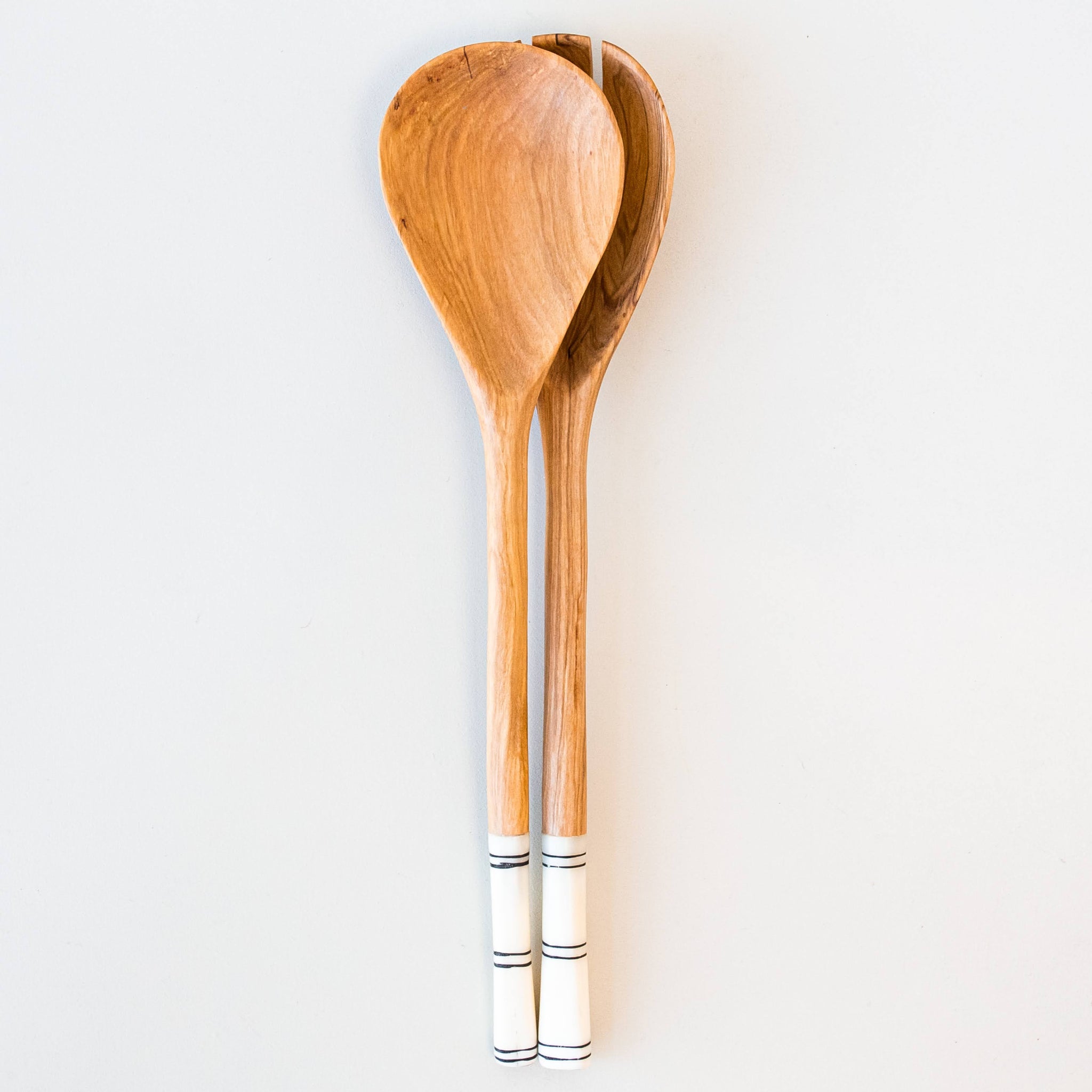 Two wooden salad spoons with white bone handles featuring black stripes, displayed against a clean white background.