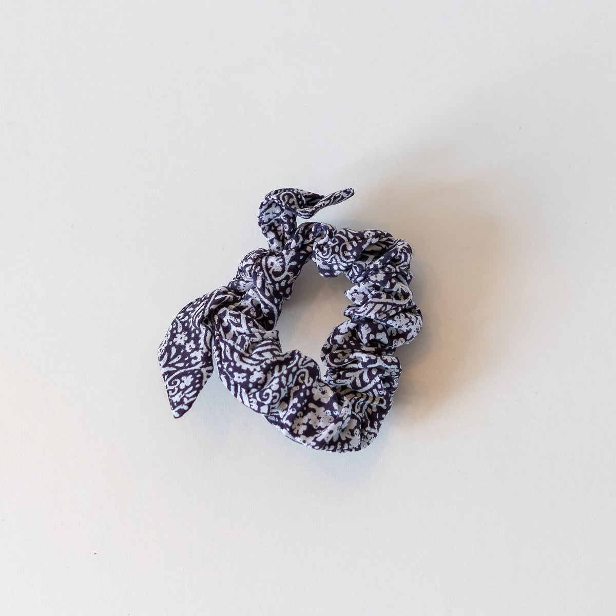Navy blue and white floral scrunchie on a white background.