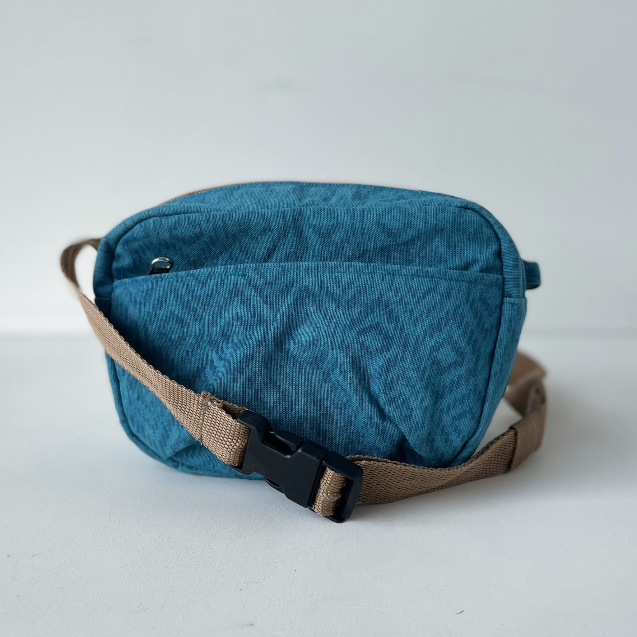 Blue patterned waist bag with a brown strap on a white background