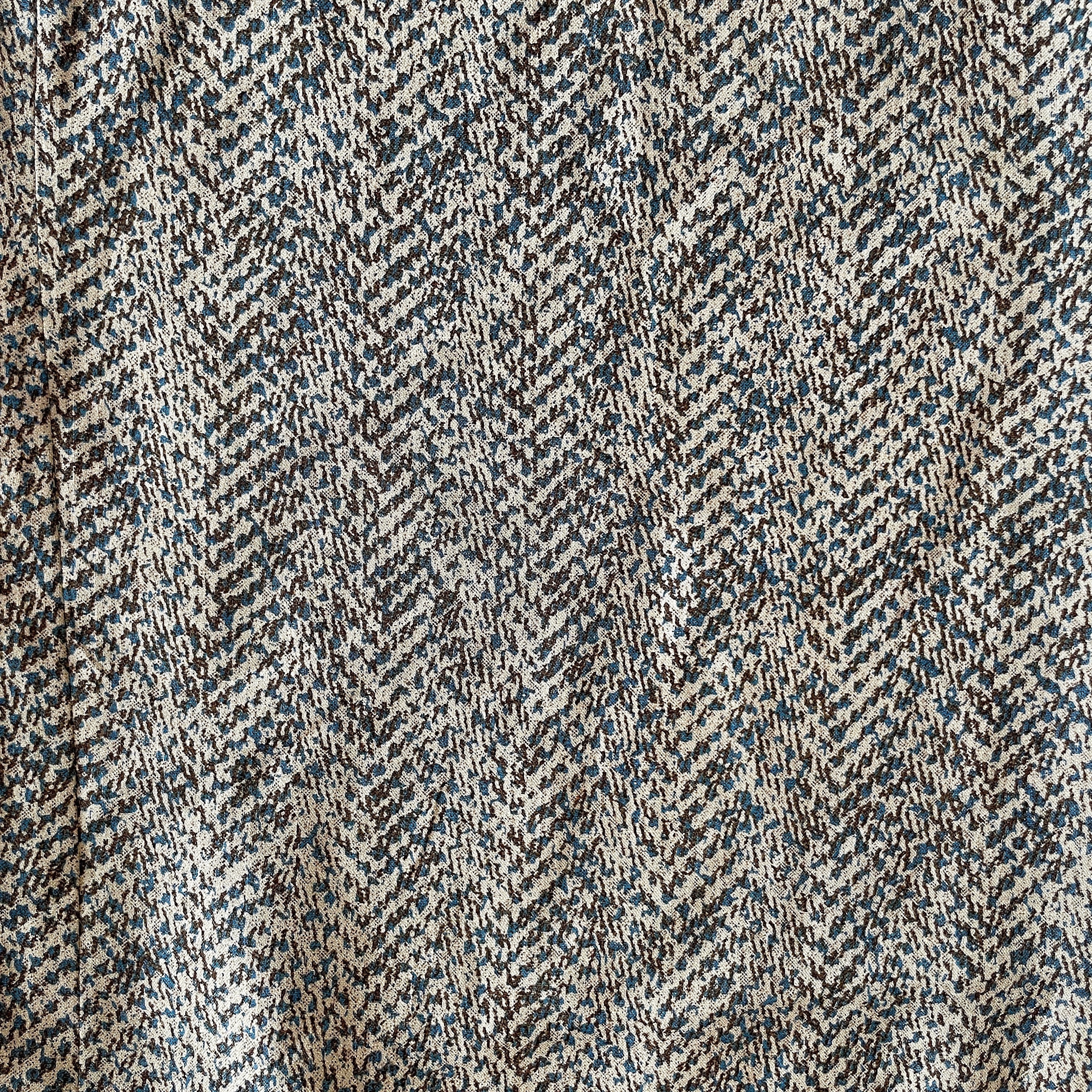 Close-up of a textured fabric with a herringbone pattern in brown, black, and beige.