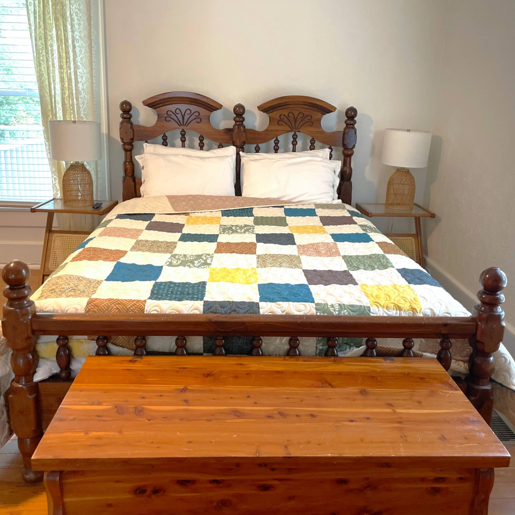 Wooden bed with checkered quilt and matching nightstands in a bedroom.