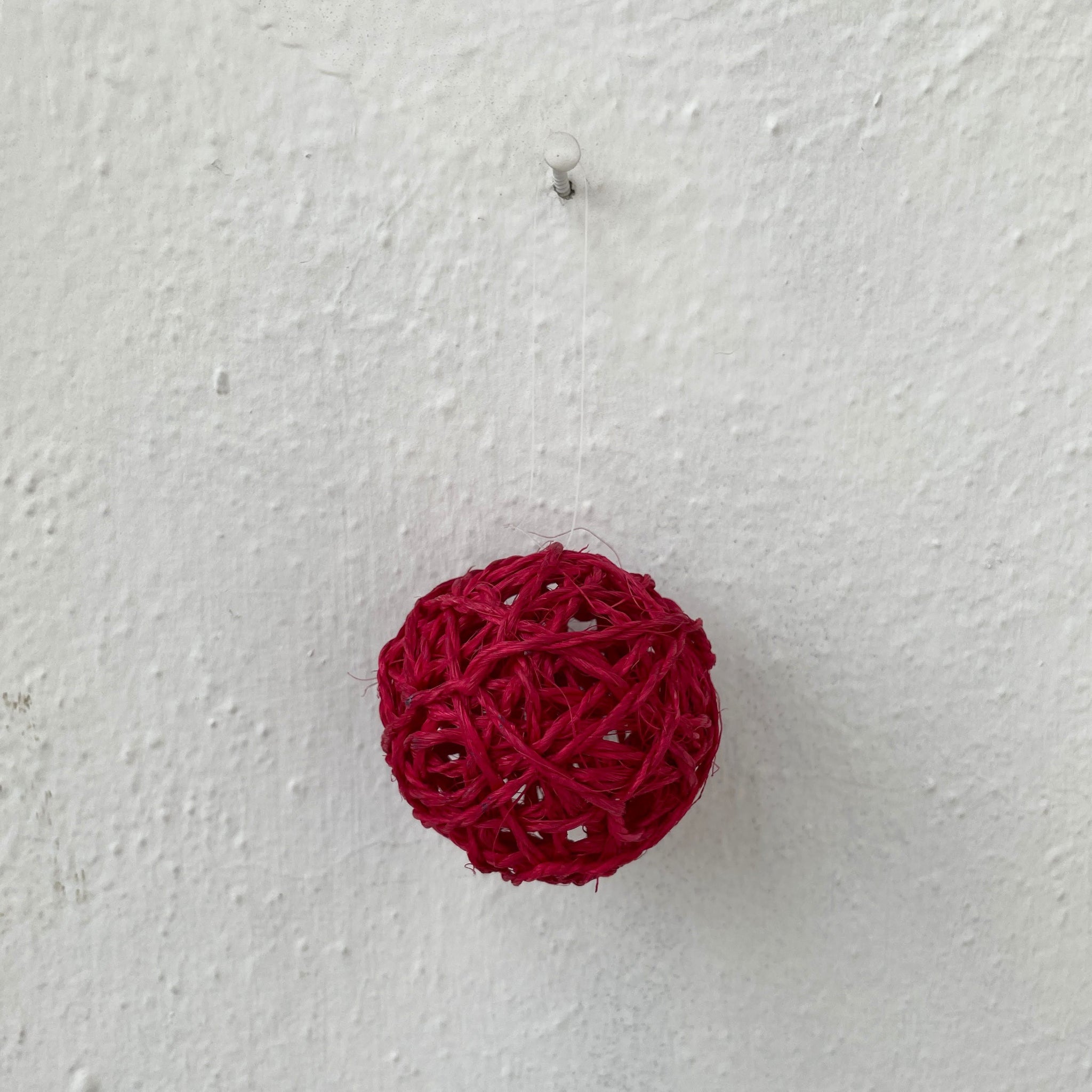 Red woven ball on a textured white background