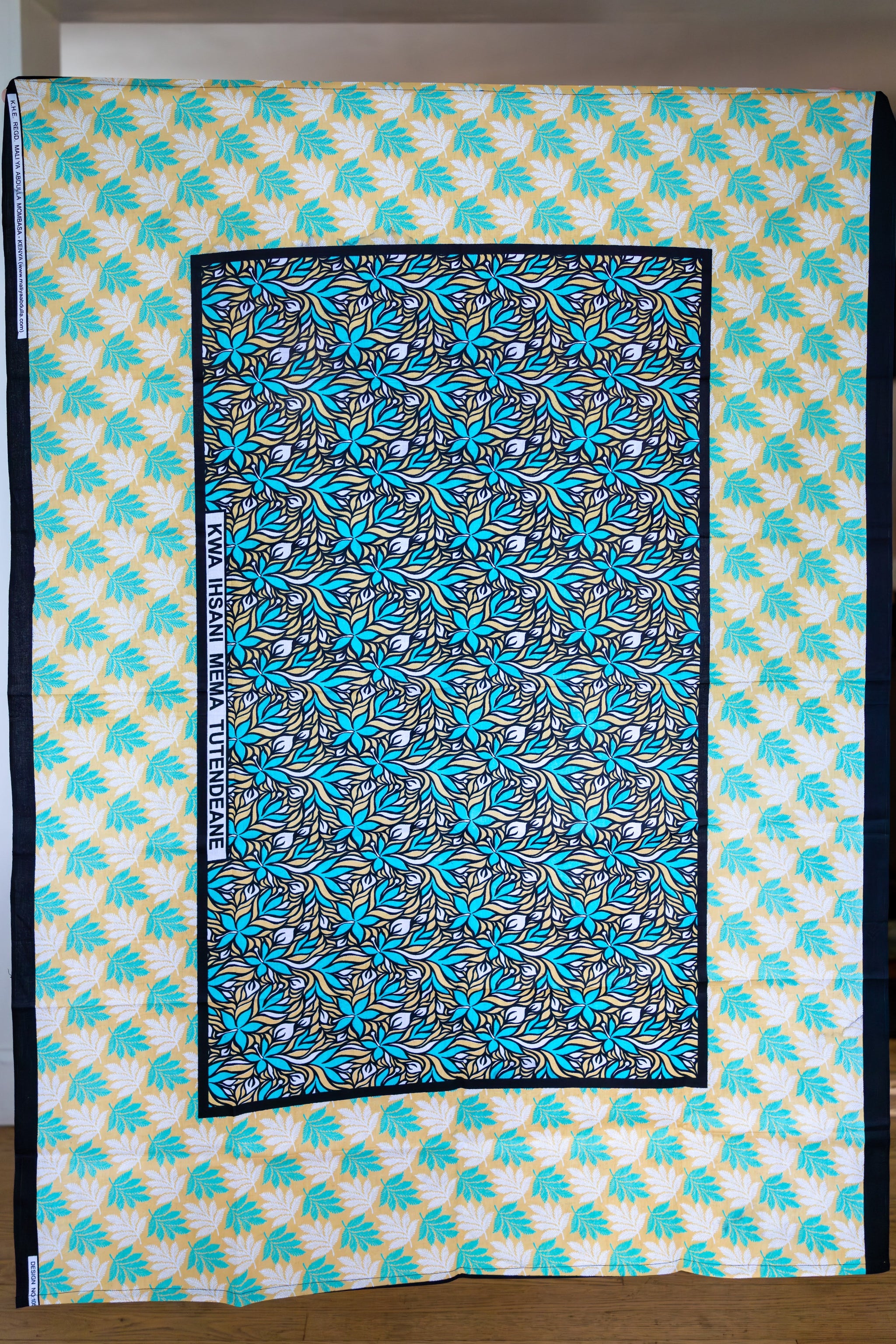 Large scarf in turquoise, white, tan, and black with hibiscus flowers and fern leaves.