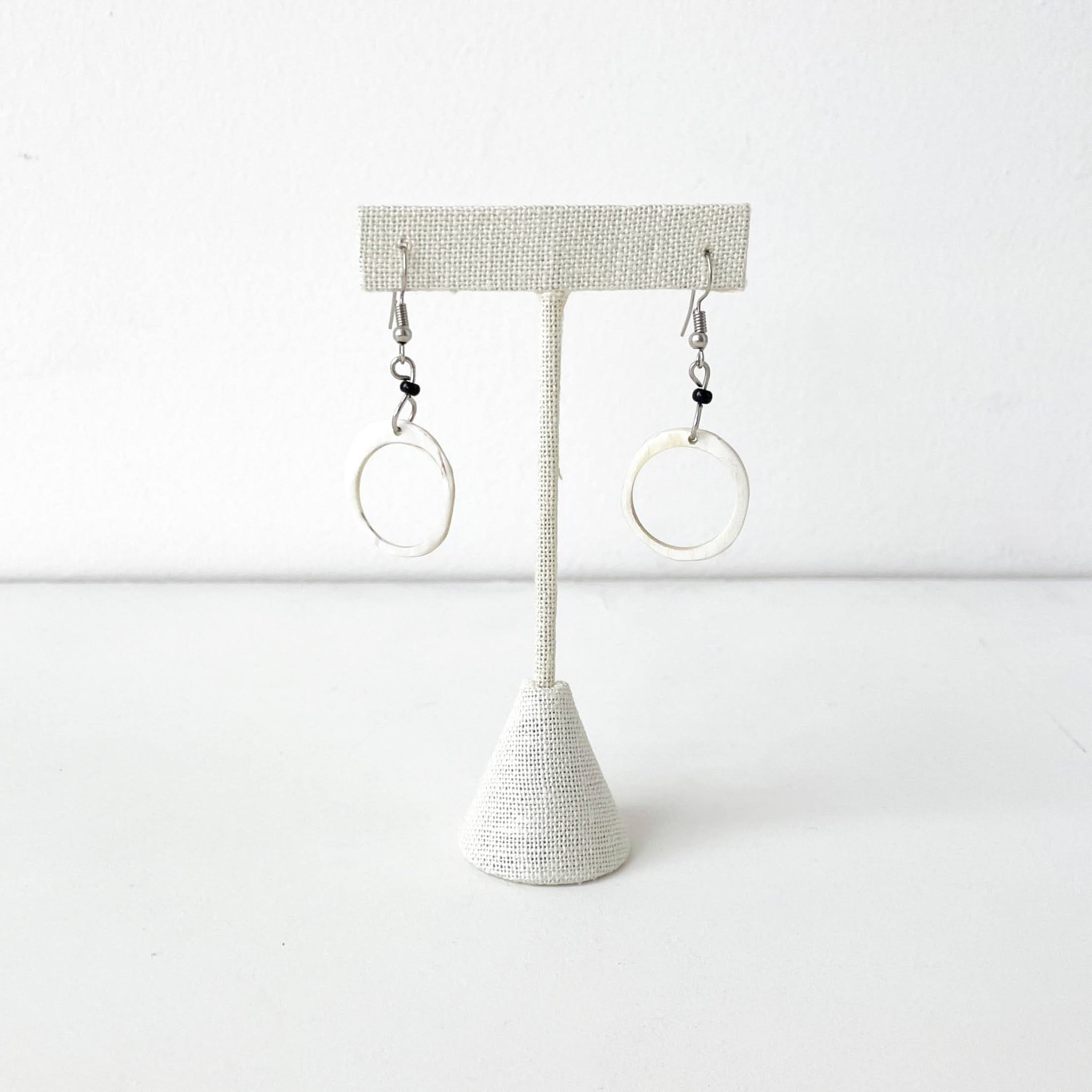 Pair of hoop earrings on a textured stand against a white background