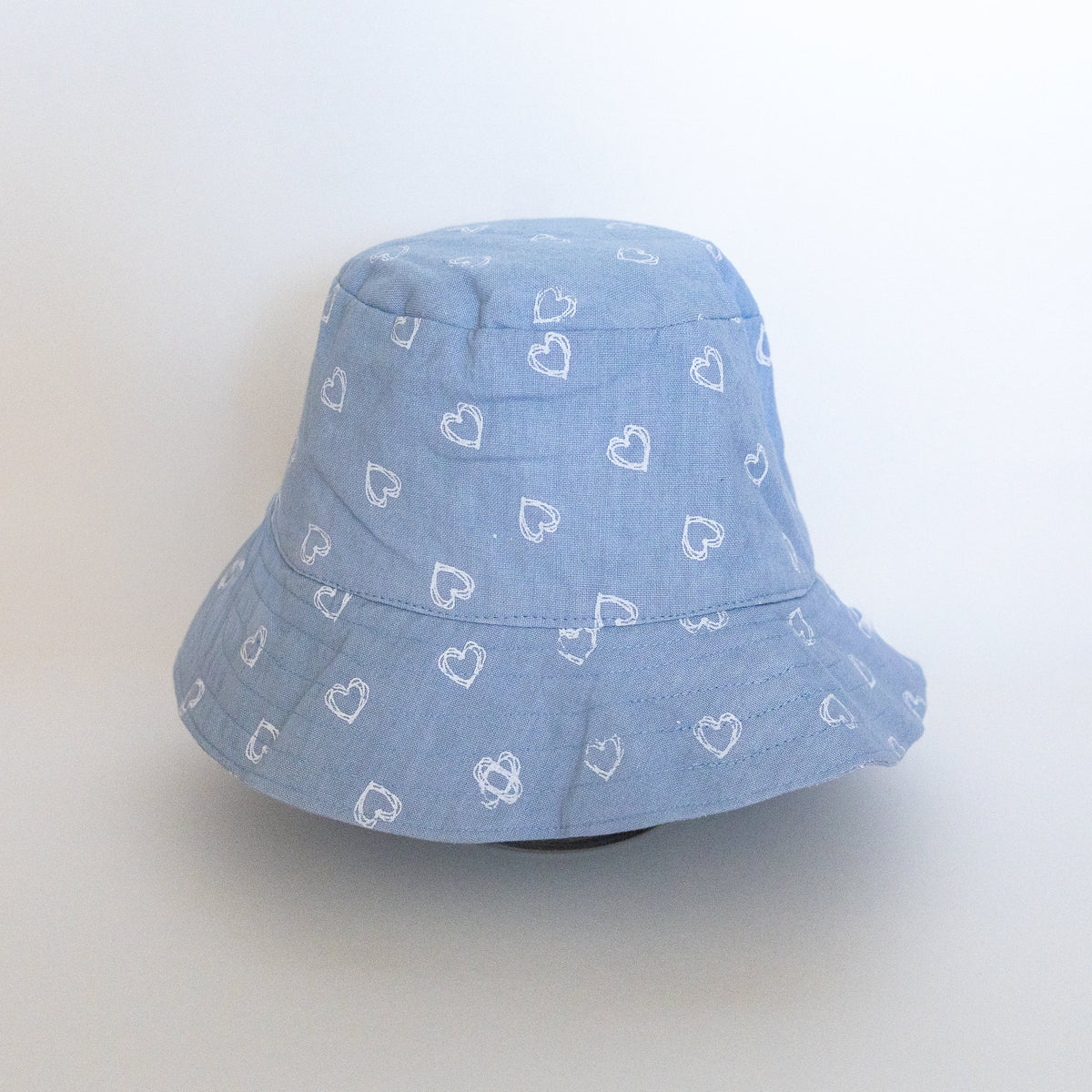 Light blue bucket hat with white hearts on a white background.