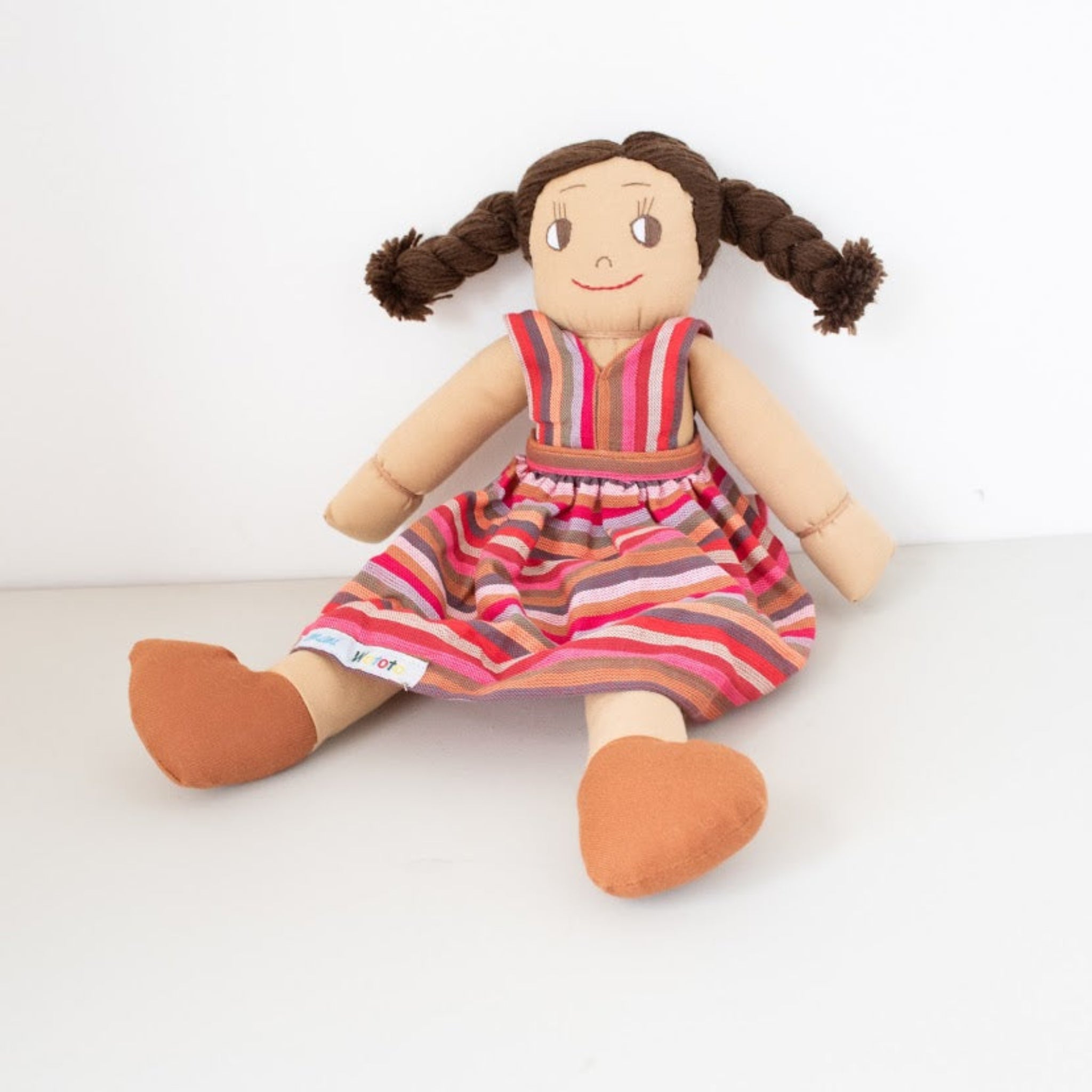 Stuffed doll with striped dress and pigtails on a white background