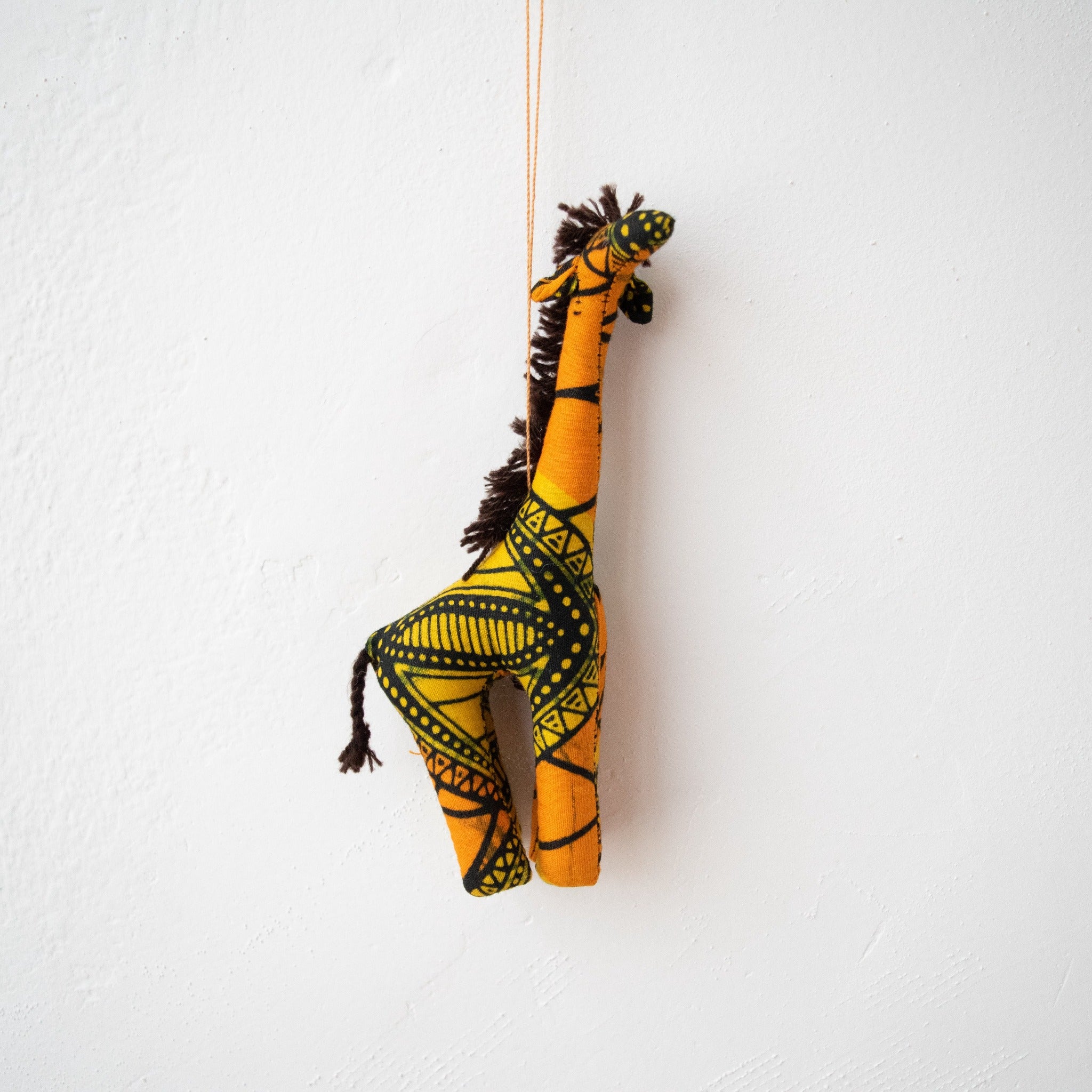 Stuffed giraffe ornament hanging on white background