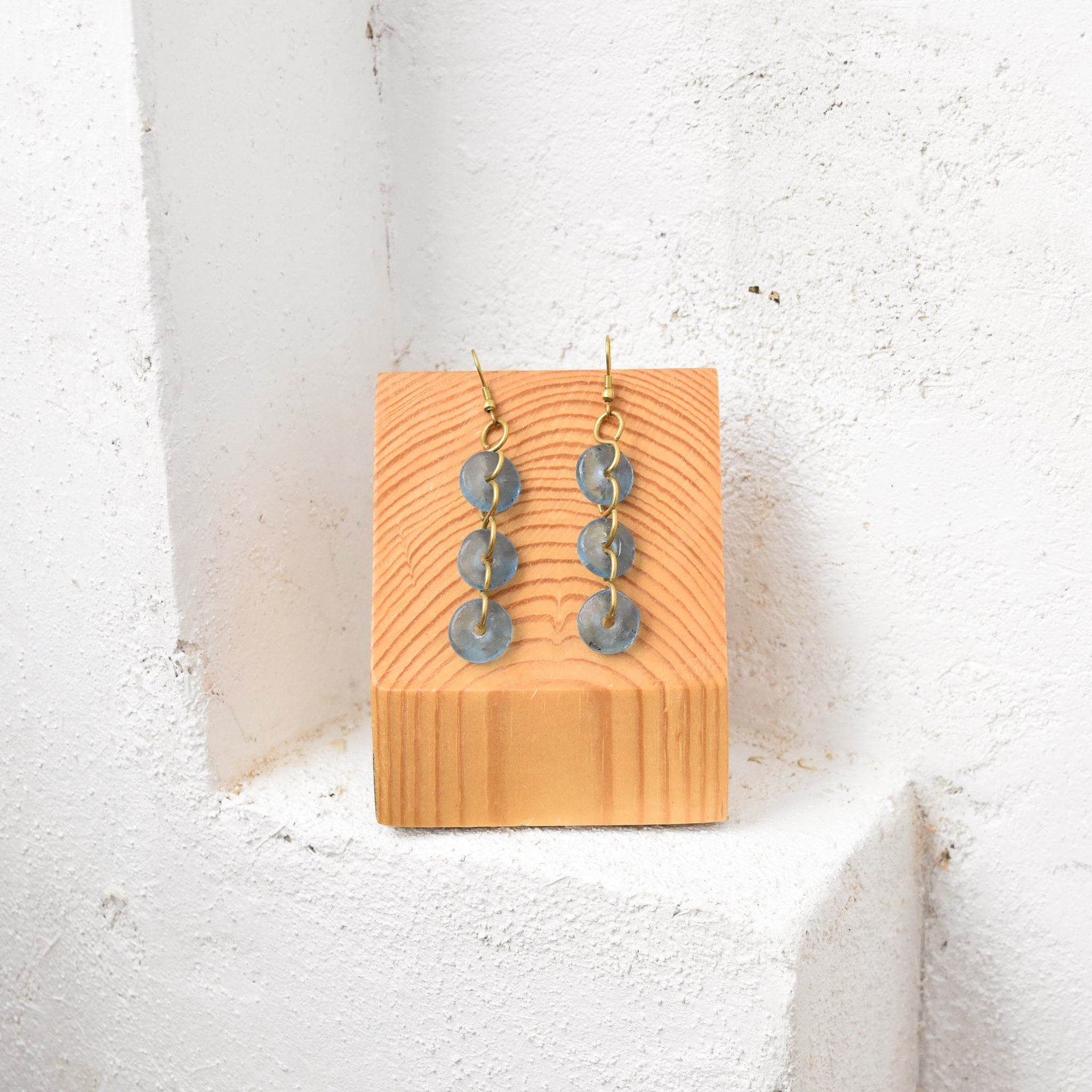 A pair of dangle earrings made with white glass beads and gold-colored metal, displayed against a light background.
