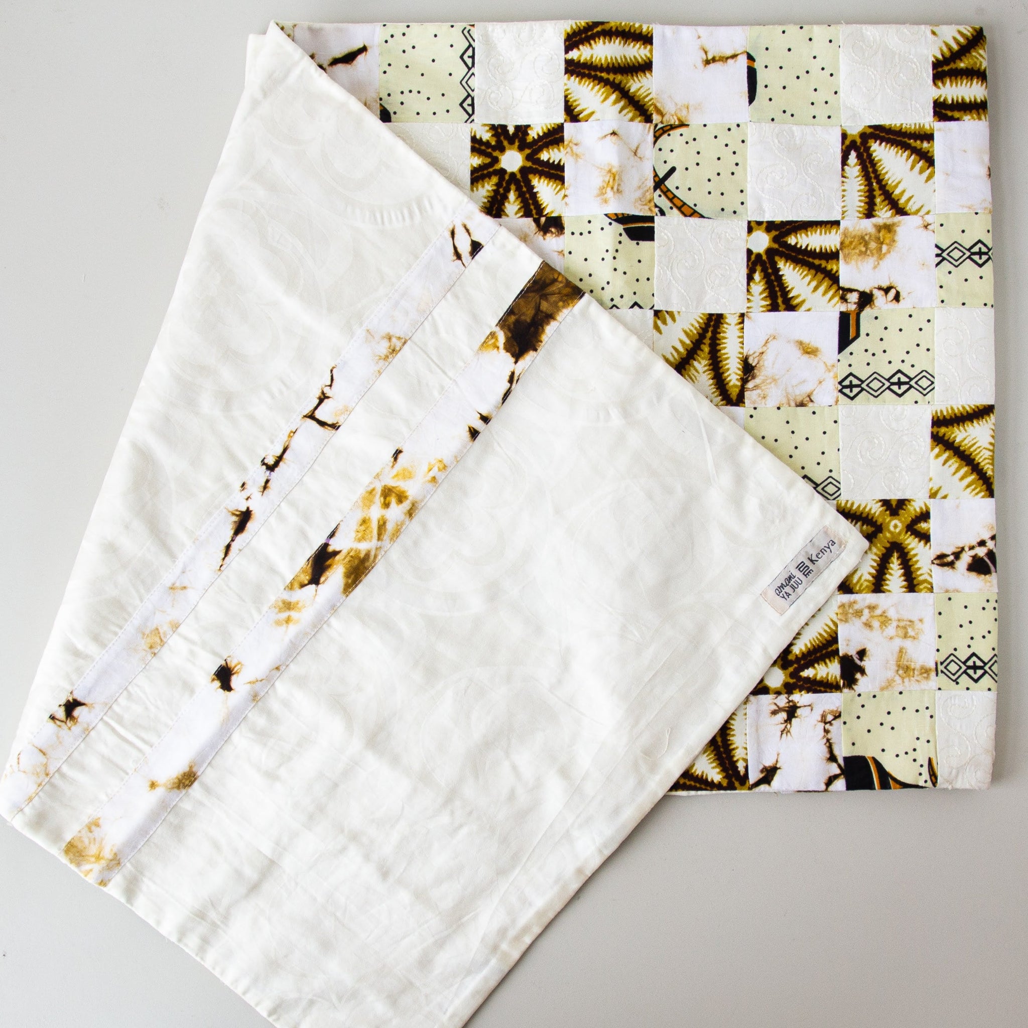 Patchwork table runner with a white background featuring African prints  and embossed cotton details.