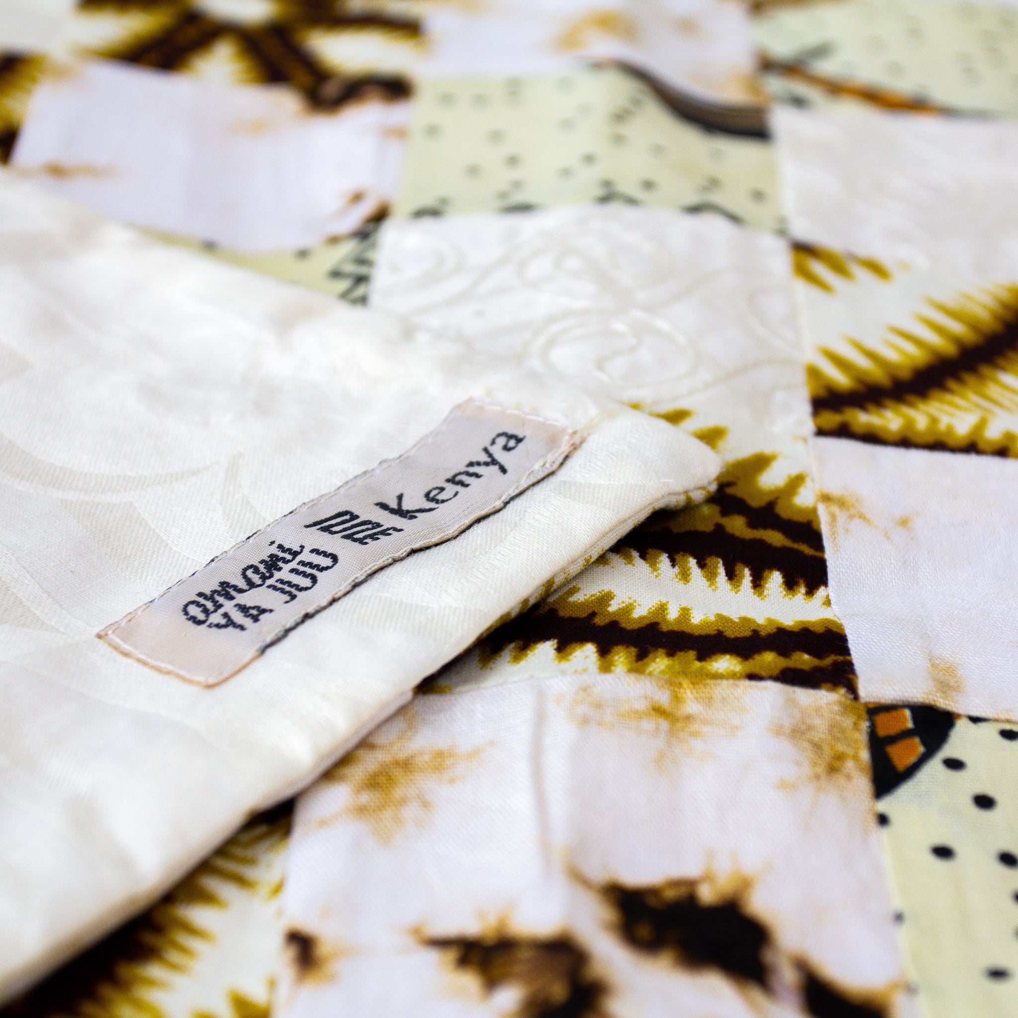 Patchwork table runner with a white background featuring African prints  and embossed cotton details.