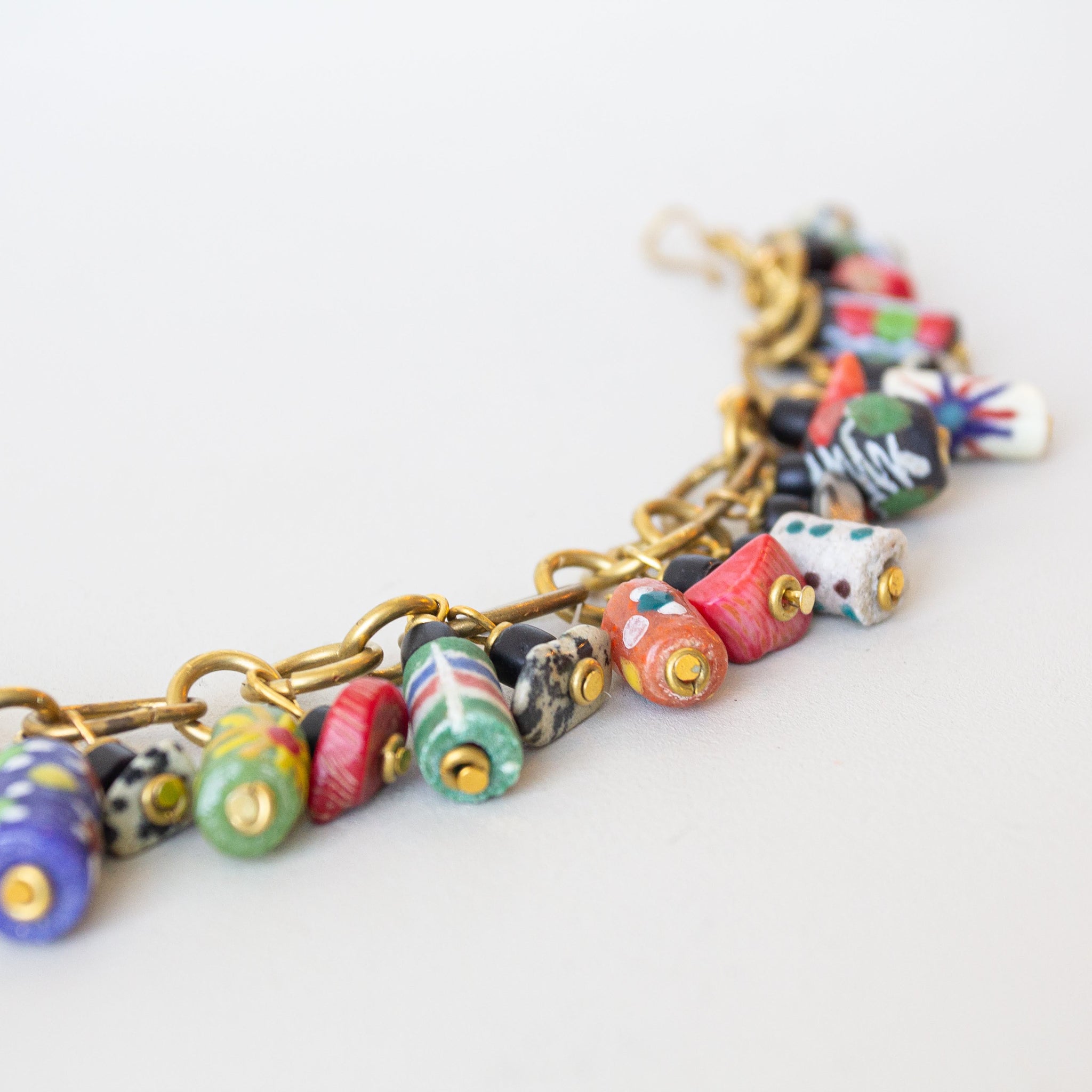 Colorful beaded bracelet with gold chain on a white background