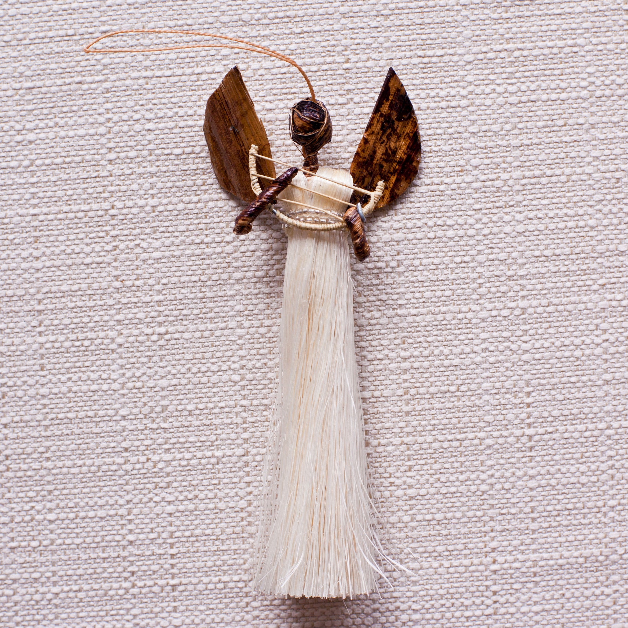 Sisal angel ornament holding harp on white background