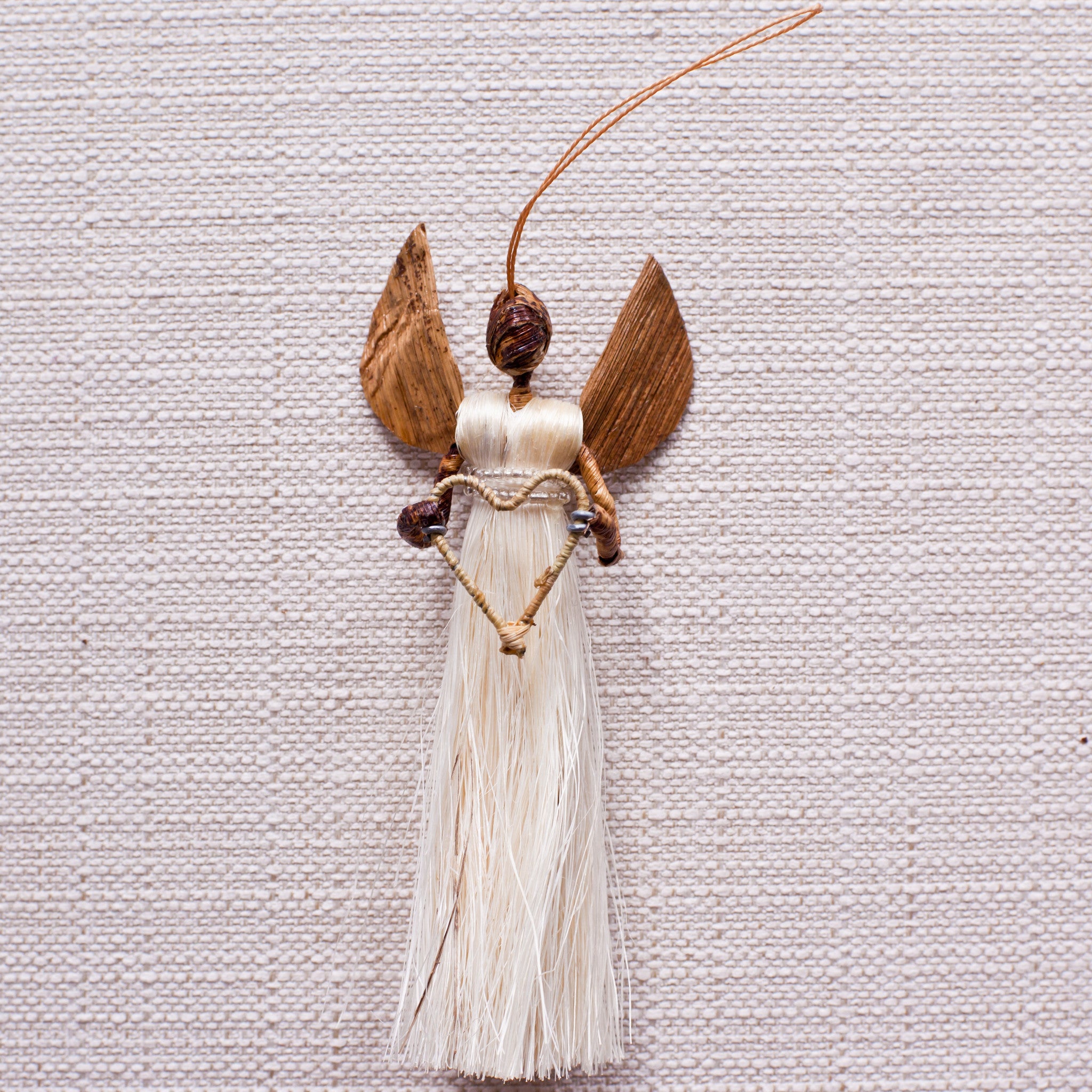 Sisal angel ornament holding heart on a white background